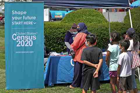Census 2020. Booth with an adult standing in front and children behind.