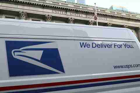 USPS 2020. Side of postal service truck with words "We Deliver For You" in blue letters.