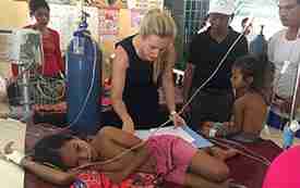 Dr. Jessica Manning works with a child patient in a clinic setting in Cambodia while others look on.