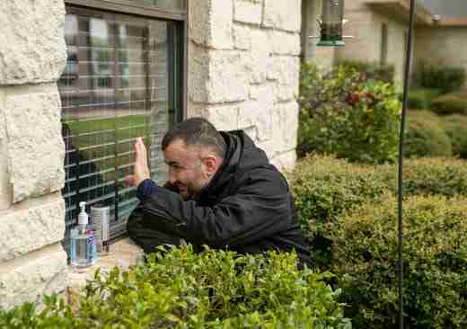 Joze Sola waves through a window to his 70-year-old mother, who lives at a senior citizens center in North Austin, Texas, on March 22, 2020.