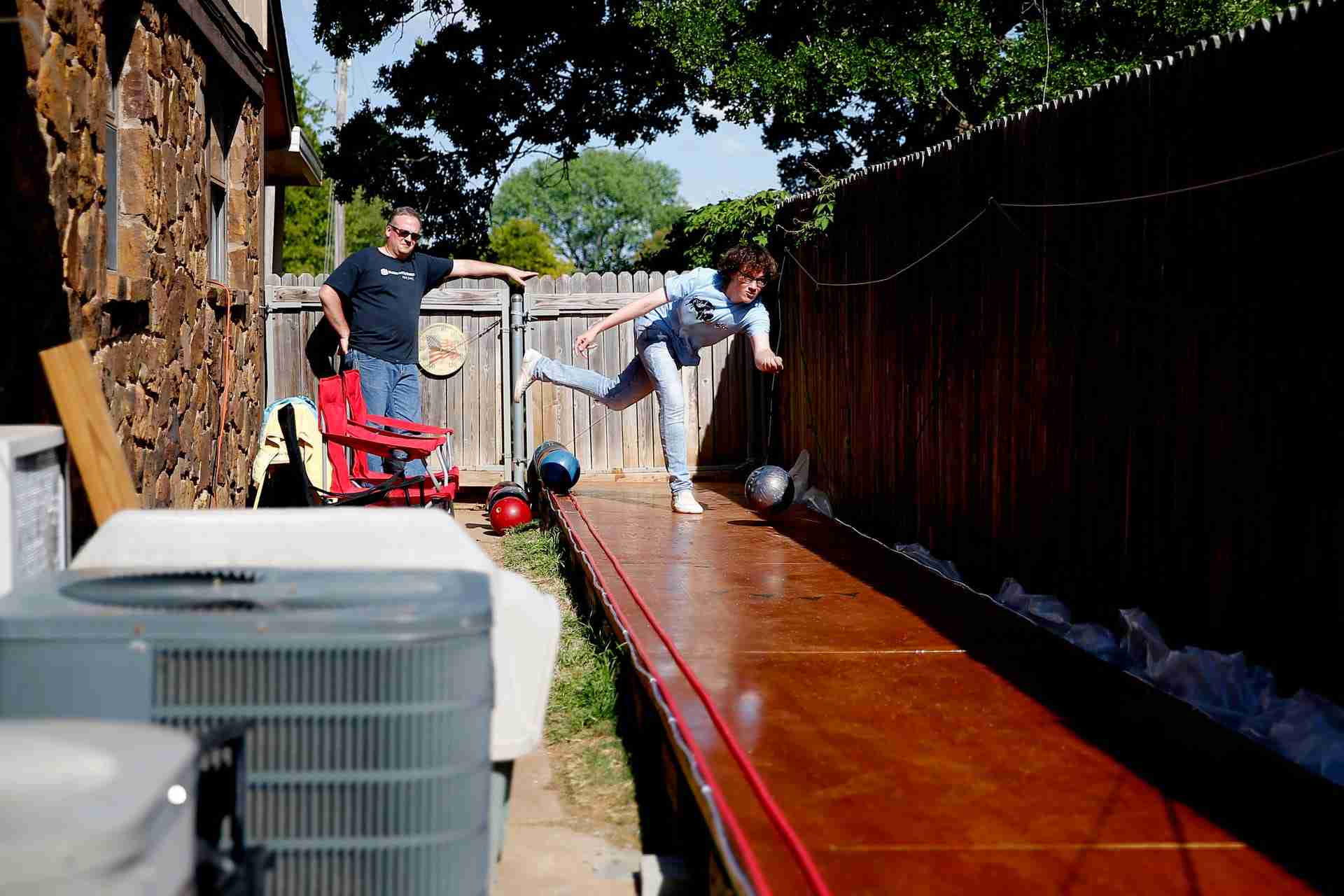 Eric Jones, 15, bowls as his dad, Heath, watches in the backyard of their Oklahoma City home, Tuesday, April 21, 2020. Health and his son Eric built a bowling lane in their backyard so that Eric, a competitive bowler, could continue to bowl while bowling alleys are closed. 