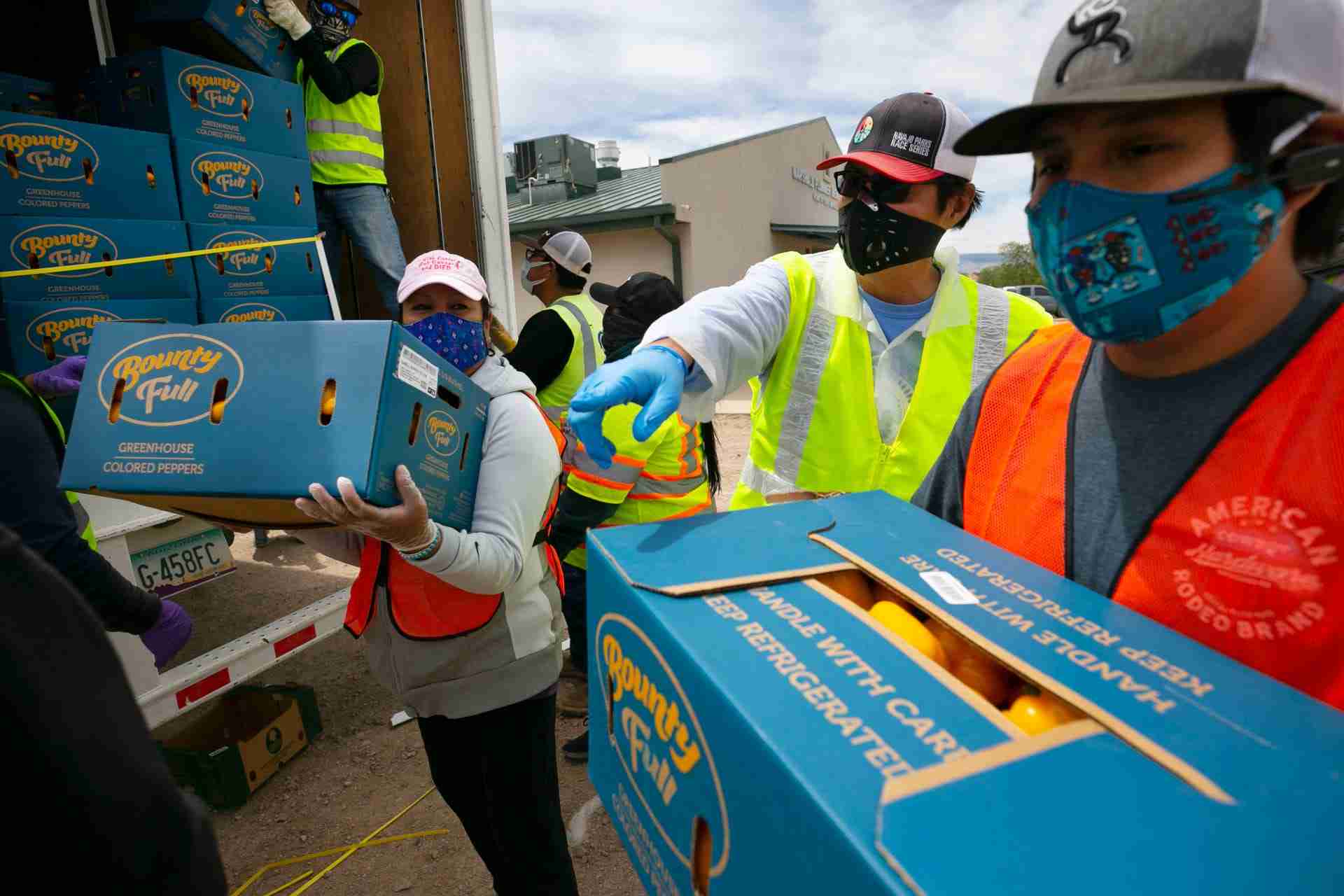 Navajo Nation President Jonathan Nez, center, and Isaiah Tsosie, right, an office specialist with the Coyote Canyon chapter, move fresh food off a truck to be distributed to community members at a food distribution point before the start of a weekend long curfew, in Coyote Canyon, N.M., on the Navajo Nation on May 15, 2020. All businesses including the 13 grocery stores on the reservation were closed during the weekend long curfew to combat the new coronavirus pandemic. The Navajo Nation has been one of the hardest hit areas from the COVID-19 pandemic in the entire United States.