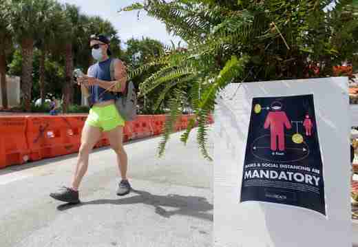A pedestrian, wearing a mask to prevent the spread of the new coronavirus, walks down Miami Beach, Florida's famed Ocean Drive on South Beach, July 4, 2020. The Fourth of July holiday weekend began Saturday with some sobering numbers in the Sunshine State: Florida logged a record number of people testing positive for the coronavirus.