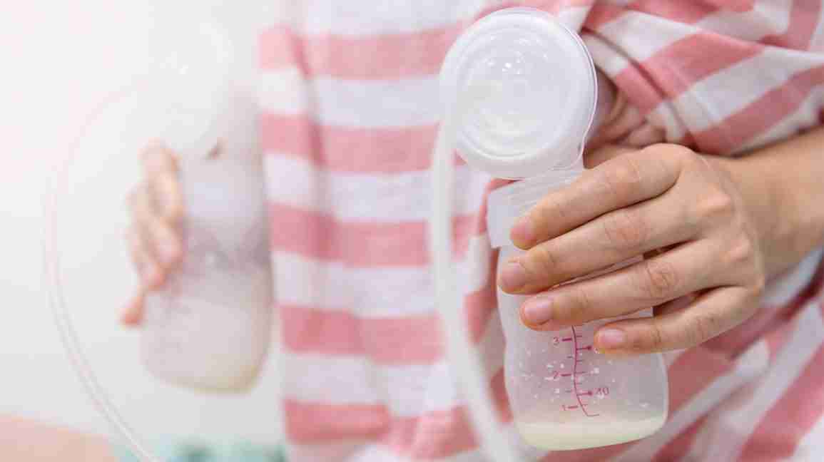 person pumping breast milk into storage bottles