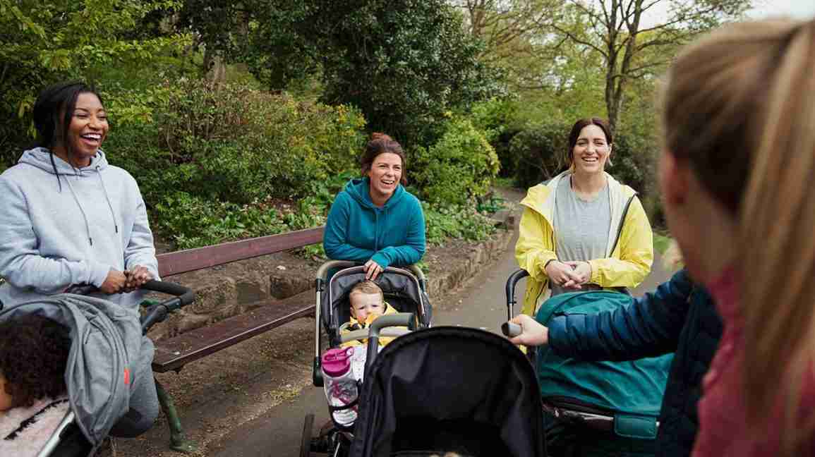mom friends pushing strollers gather to talk