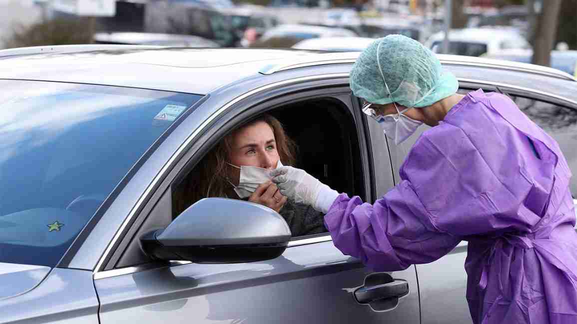 A health care worker tests a woman, sitting in her car, for symptoms of the novel coronavirus. 