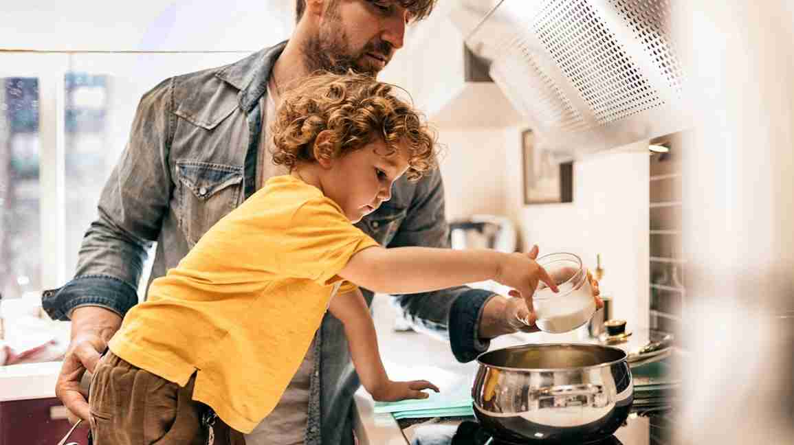 man cooking with child in the kitchen