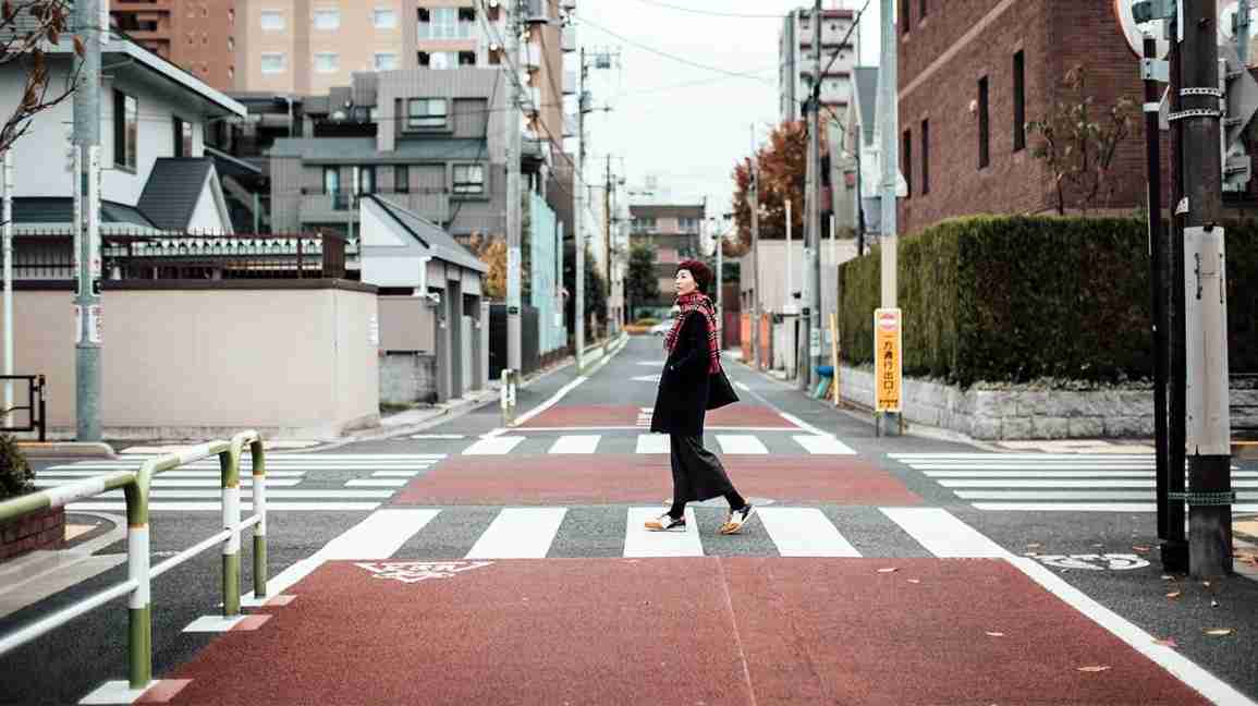 a woman walks slowly across city streets