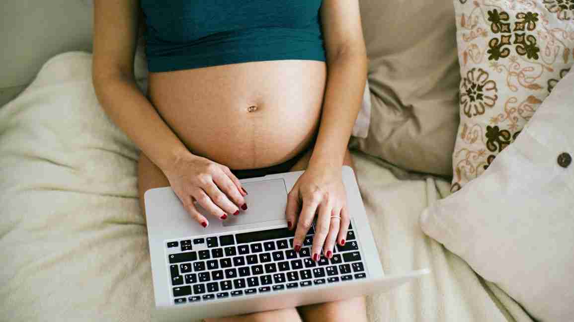 Pregnant person bed with laptop
