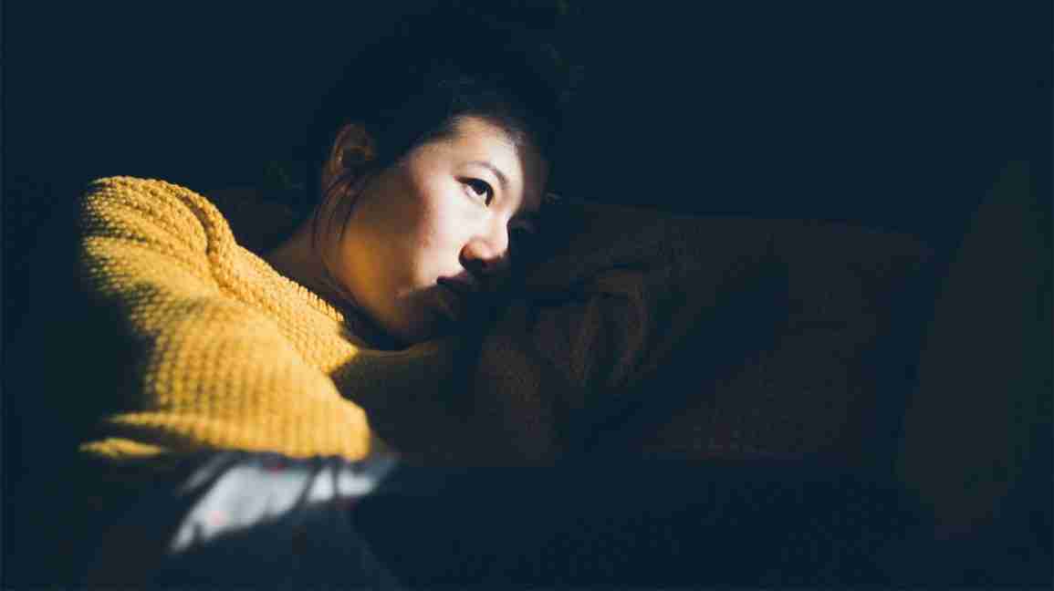 Woman lying in darkened room due to migraine
