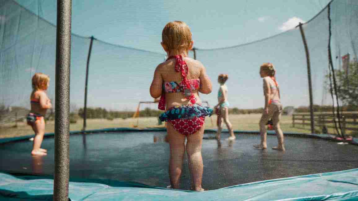 Toddler watching kids play on trampoline