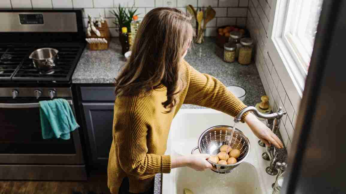 a woman rinsing hard-boiled eggs