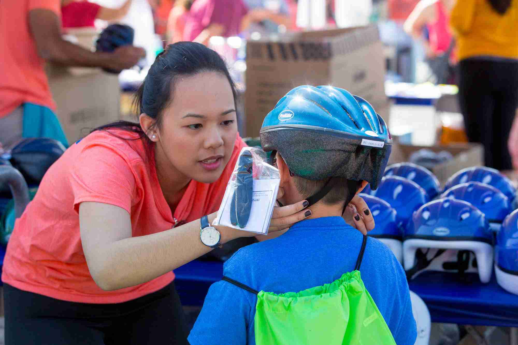 TMC volunteer fitting bicycle helmet on child at Be Safe Saturday