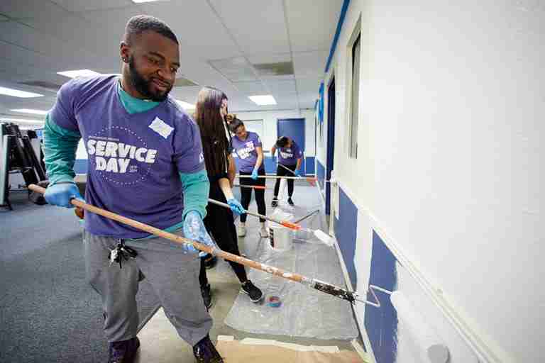 A student helps paint the Boys & Girls Club for Services Day 