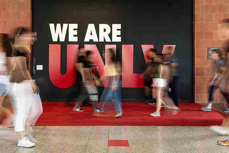 Students walking past wall that says We Are U.N.L.V.